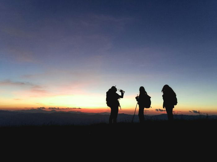 Wanderer trinken bei Sonnenaufgang